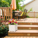 White lattice planter positioned on wooden deck steps holding a colorful mixed flower arrangement