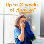 Child smelling a blue shirt with overlay text claiming up to 21 weeks of freshness, Purex Crystals branded lifestyle image