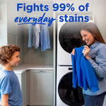 Mother showing a blue garment to a child in front of a stacked washer and dryer with ‘Fights 99% of everyday stains’ headline