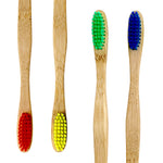 Close-up of four bamboo toothbrush heads with red, yellow, green and blue bristles on white background