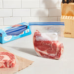 Kitchen scene with a clear quart freezer bag holding a steak, packaged box in background and a second steak on butcher paper.