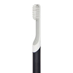 Angled close-up of Quip toothbrush head and neck showing bristles, grey accent and charcoal handle on white background