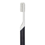 Close-up vertical view of a Quip charcoal toothbrush handle and white brush neck against a white background