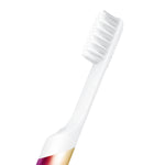 Close-up of a white toothbrush neck and soft bristle head attached to a rainbow-metal quip handle