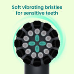 Top-down close-up of a Quip Rev round brush head showing black, gray and teal bristle clusters on pale background