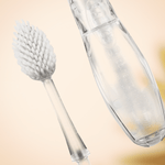 Close-up view of a detached Radius Tour replaceable toothbrush head and the transparent handle body on a warm background