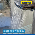 Showerhead spraying water onto a wet shower door, with water droplets on glass and a Rain‑X logo and rinse instruction banner.