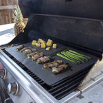 Grill with a Range Kleen liner on the grates holding bacon-wrapped jalapeños, asparagus and pineapple pieces.