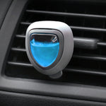 Close-up of a triangular car vent air freshener with blue gel insert clipped to a vehicle air vent.