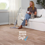 Lifestyle scene with a woman seated on a sofa, a Rejuvenate PowerMax spray mop on the floor and wood-floor-safe badge