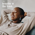 Smiling relaxed person leaning back with text 'breathe in the fresh' overlaid on the photo