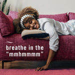 Person reclining on a couch smiling and appearing relaxed on a textured magenta sofa with overlaid promotional text.