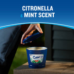 Hand removing the blue lid from a Cutter outdoor candle on a stone surface with ‘citronella & mint scent’ text.
