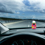 Renuzit Forever Raspberry gel air freshener shown on a car dashboard with stylized scent swirls and an open highway visible through the windshield