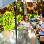 RESCUE! TrapStik hanging from an umbrella pole on a glass patio table with blurred people in background
