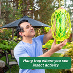 Person hanging a bright green RESCUE! TrapStik trap from a cord in a backyard setting with instructional caption overlay