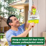 Person hanging a RESCUE! Yellowjacket Trap from a hook outside, smiling and positioning the clear packaged trap