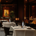 Restaurant interior with table settings and a stainless table torch placed on a white-clothed dining table