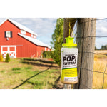 Reusable POP! Fly Trap hanging from a fence post outdoors with a red barn blurred in the background