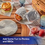 Sandwiches and plates wrapped in embossed fireworks-pattern foil displayed on a picnic-style wooden table