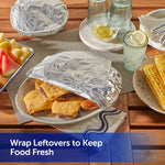 Plate of cheeseburgers wrapped with embossed aluminum foil featuring a fireworks pattern alongside corn and drinkware