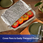 Baking dish partially covered with embossed heart-patterned aluminum foil over stuffed bell peppers on a dining table