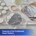Round plates partially covered with embossed aluminum foil printed with heart pattern on a tabletop baking scene