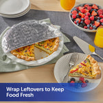 Quiche on a plate partially covered by embossed heart-patterned foil next to a bowl of mixed berries and orange juice