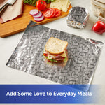 Sheet of embossed heart-patterned foil used as a placemat under a sandwich with a wrapped square sandwich in background