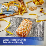 Loaf cake placed on embossed heart-patterned foil with a wrapped gift on a cutting board and yellow ribbon accents