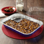 Reynolds Kitchens blue aluminum baking pan with brownies on red placemat and clear plastic lid nearby