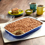 Blue disposable Reynolds Kitchens aluminum pan filled with layered dessert on a wooden table setting