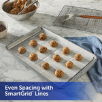 Cookie dough scoops placed on a parchment-lined baking sheet featuring Reynolds Kitchens SmartGrid spacing lines