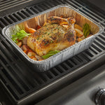 Aluminum Reynolds utility pan on a grill holding a roasted whole chicken with vegetables