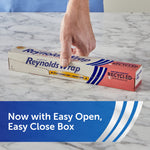 Hand pressing down on a Reynolds Wrap recycled aluminum foil box on a marble surface with easy open box callout