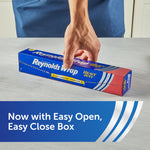 Hand closing a Reynolds Wrap heavy duty foil box on a light countertop with text about easy open, easy close box