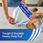 Person pulling a sheet of Reynolds Wrap heavy duty aluminum foil from the box on a kitchen countertop with spices nearby