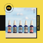 Row of five blue Scent Bomb spray bottles including Black Cherry flavor on a seaside background with branded graphic