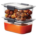 Two stacked clear Rubbermaid Brilliance rectangular containers with gray clips, one filled with roasted potatoes and the other with sauce.