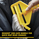 Gloved hand operating the yellow Invader side-gate mop head release while a mop head is being removed