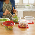 Lifestyle shot of multiple clear Rubbermaid containers with red lids on a kitchen counter being used for salad
