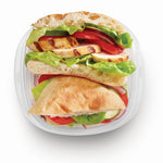 Overhead view of a sandwich inside a clear Rubbermaid TakeAlongs square container on a white background