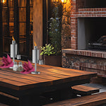 Wooden dining table with two stainless table torches, napkin decorations and condiments in a rustic setting