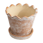 Front view of a scalloped-edge terracotta planter with visible cream interior and saucer beneath