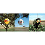 Three inflated scare-eye balloons hanging outdoors showing yellow, white and black color variants with target-style eye prints.