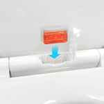Rectangular orange-red scent pod held above an open toilet hinge refill compartment with a downward arrow