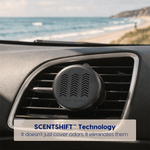 Scent Theory black car vent diffuser clipped to a vehicle vent with a blurred beach visible through the windshield.