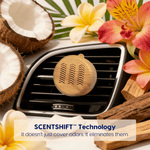 Woodgrain Scent Theory vent diffuser attached to a car vent with coconuts and tropical flowers arranged around it