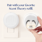 Hand inserting a Scent Theory Velvet Vanilla fragrance refill into a wall plug-in diffuser shown beside the plugged diffuser