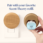 Hand inserting a sea salt linens fragrance refill into a wood-grain Scent Theory plug-in diffuser beside a mounted diffuser